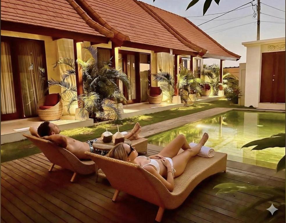 two people laying on chairs by a swimming pool at Parama Swaha Villa Near Canggu in Munggu