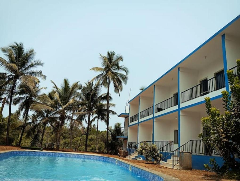 a resort with a swimming pool and palm trees at Grace villa in Mandrem