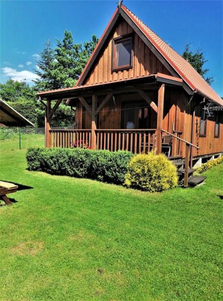 a large wooden cabin with a porch on the grass at Kruklanki Domek in Kruklanki