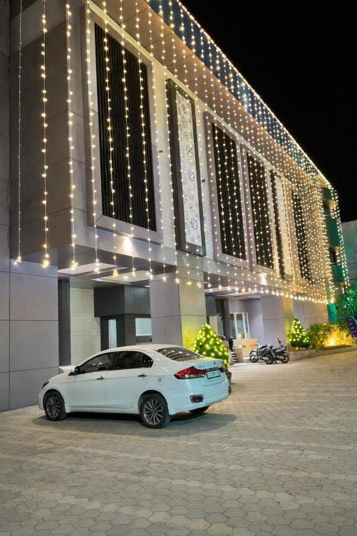 a white car parked in front of a building with lights at Hotel Shree Abhishek in Bārāmati