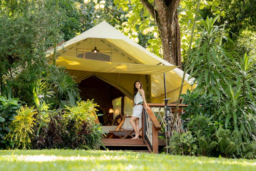 a woman standing in front of a yellow tent at Hintok River Camp in Sai Yok