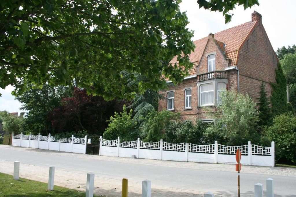 a white fence in front of a house at B&B Ter Brugge in Jabbeke