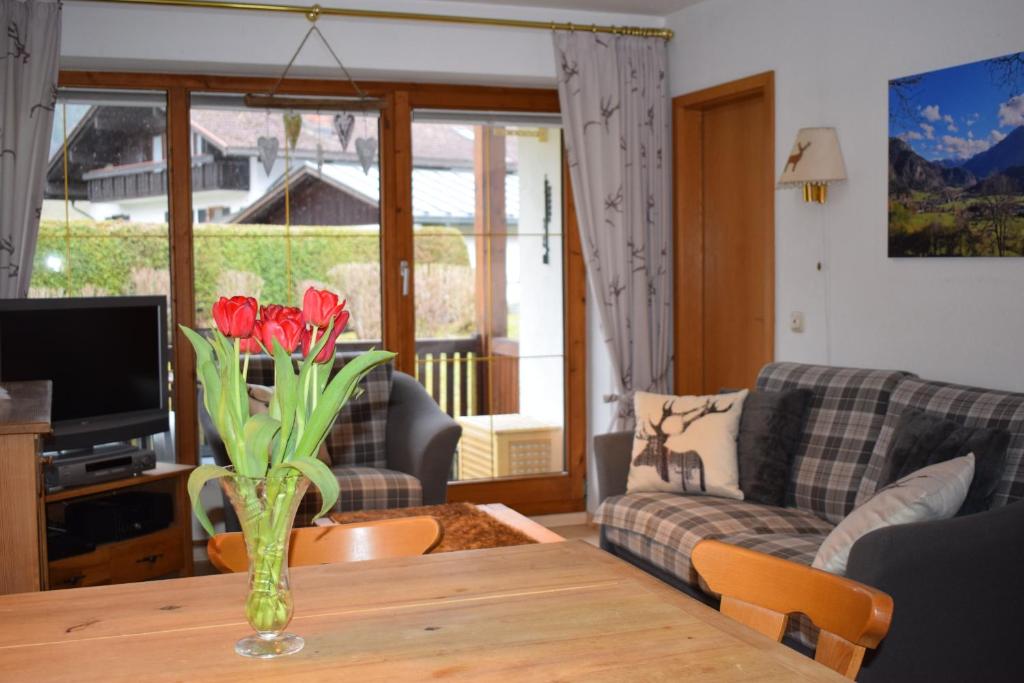 a living room with a vase with red flowers on a table at Allgäuschönheit inkl BadHindelangPlus Karte in Bad Hindelang