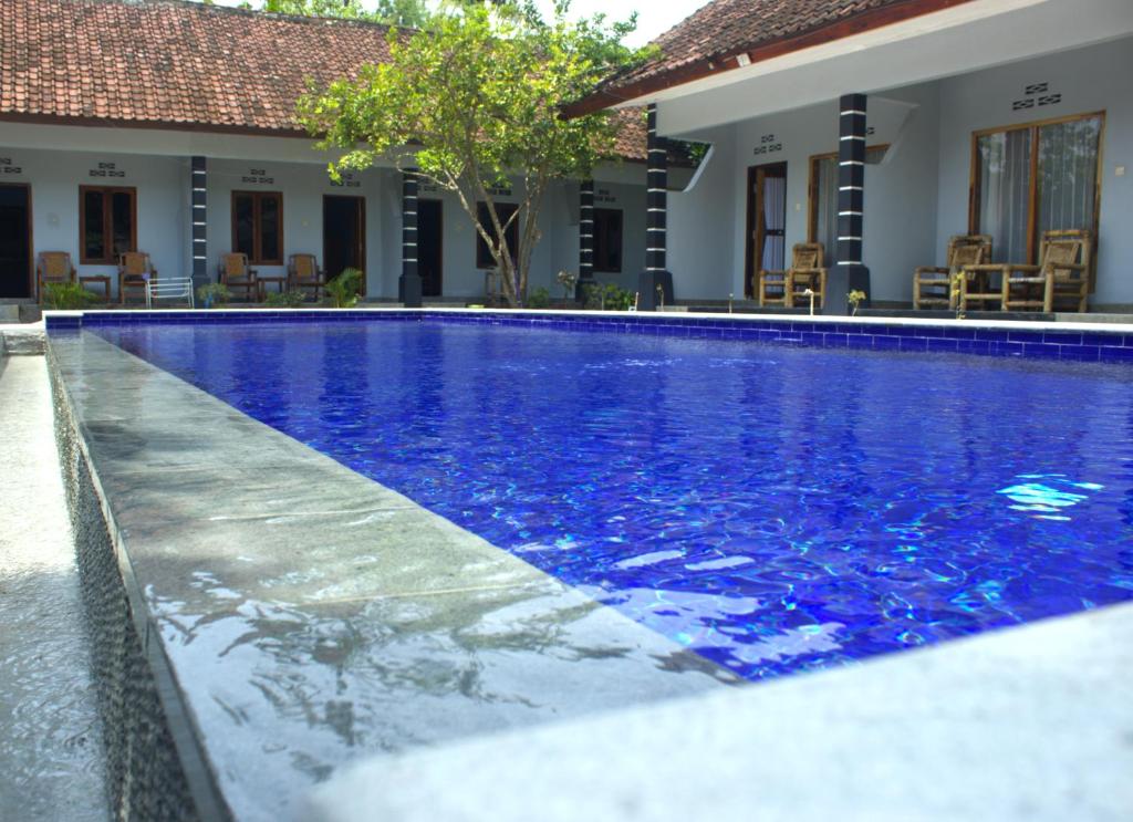 a swimming pool with blue water in front of a house at Sawe Homestay in Kuta Lombok