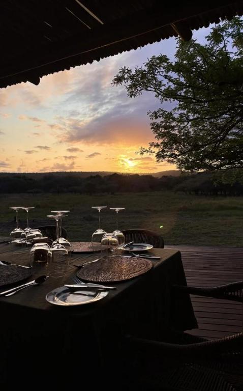 a table with chairs and a sunset in the background at Mkhuze Trails Lodge in Hluhluwe