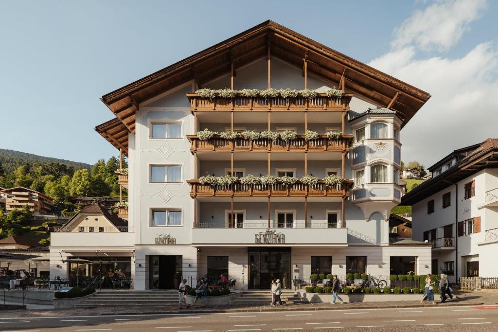 a large white building with a balcony at Hotel Genziana in Ortisei