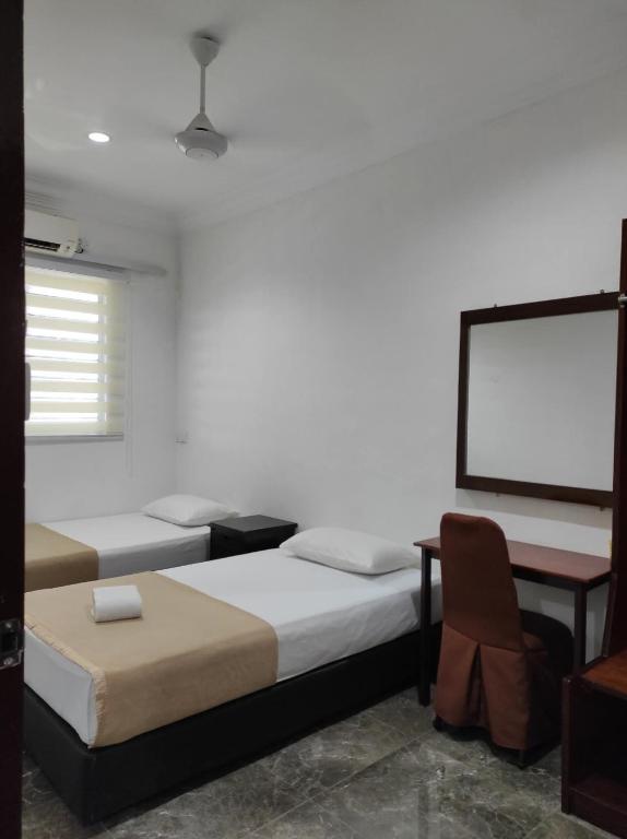 a room with two beds and a white wall at House 21 in Lahad Datu