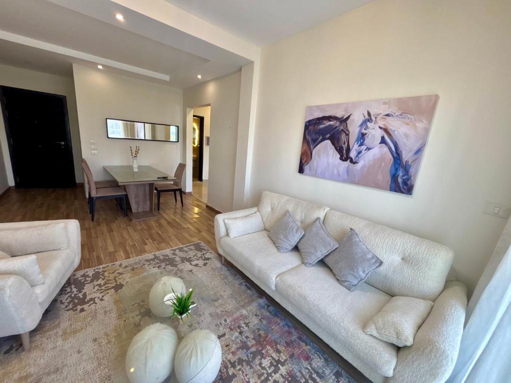 a living room with a white couch and a table at Cozy crystal lounge in Sheikh Zayed