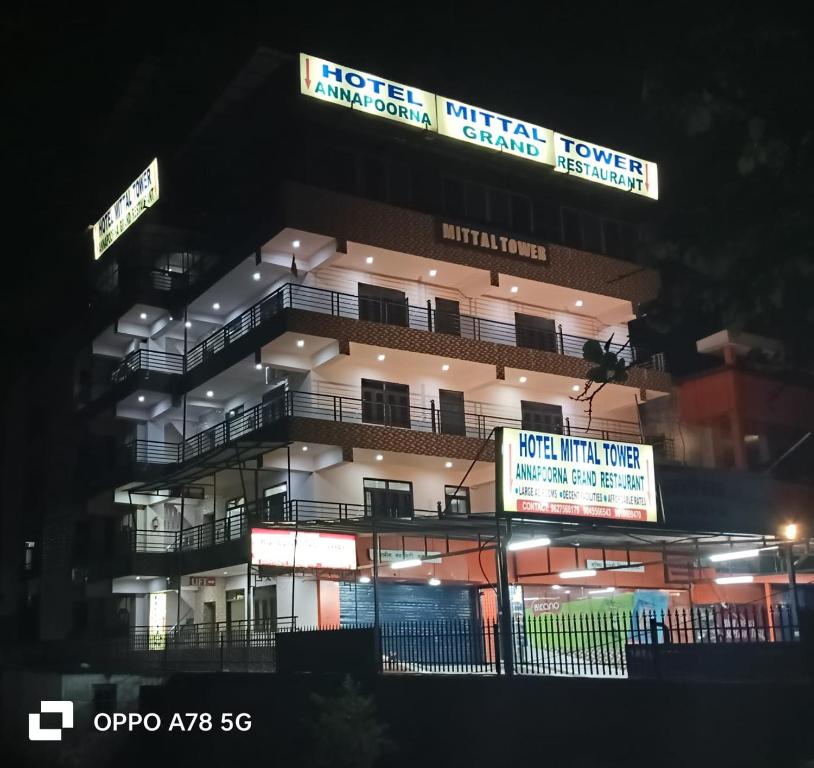 a tall building with signs on it at night at Hotel Mittal Tower in Jhājra