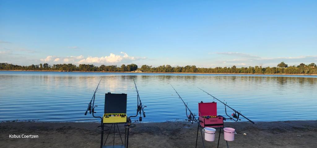 three chairs sitting on the shore of a lake at Buffelslaagte at the Vaal in Oranjeville