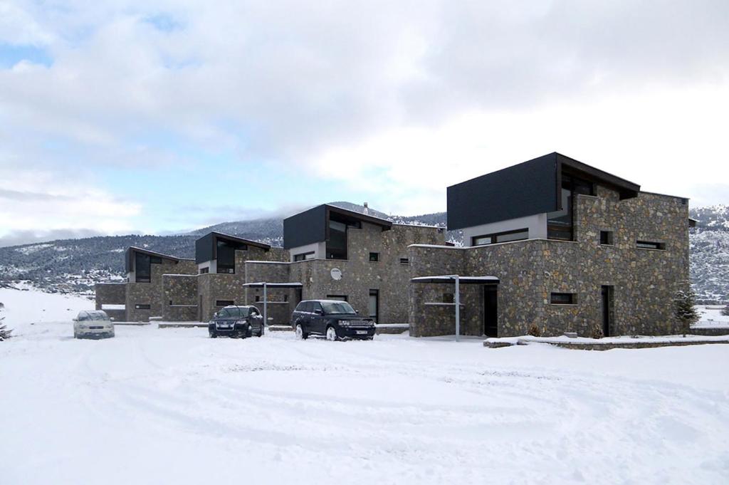 a large building with two cars parked in the snow at Arachova Livadi in Arachova