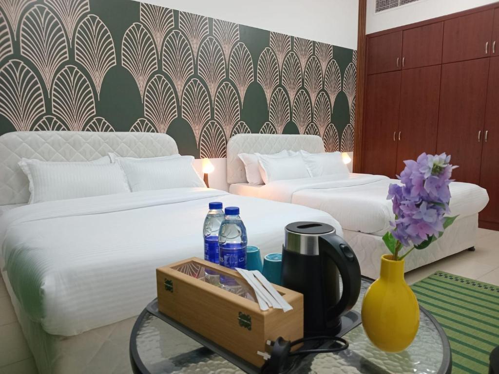 a hotel room with two beds and a table with drinks at AlWasl Guesthouse by PHM in Dubai