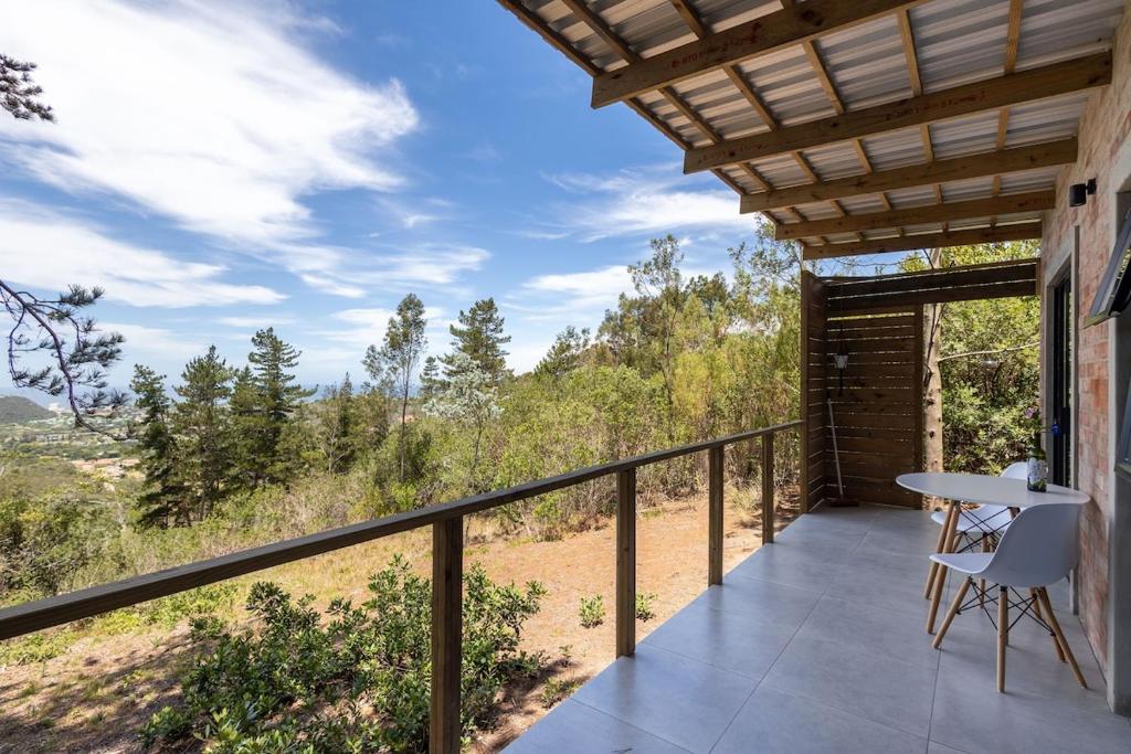 a balcony of a house with a table and a view at Pine Forest Retreat Cabin in Plettenberg Bay