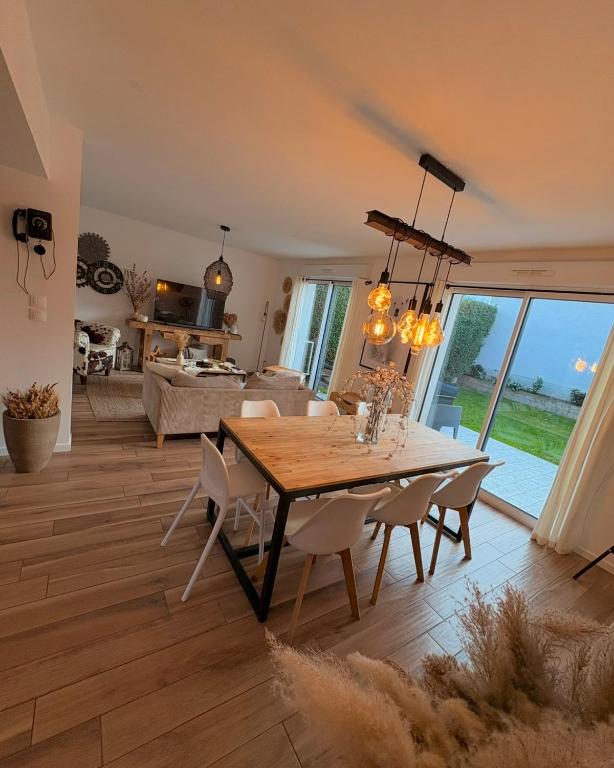 a dining room and living room with a table and chairs at Maison moderne entre terre et mer in Coquelles