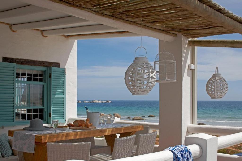 a dining table on the beach with a view of the ocean at Dankbaar Holiday Home in Paternoster