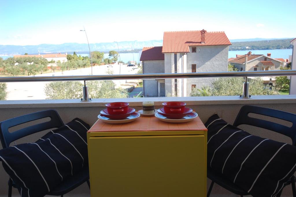 una mesa amarilla con 2 tazas rojas y sillas en el balcón en Apartment Vesna, en Porat