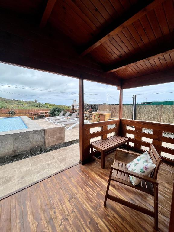 a porch with a bench and a table on a deck at Betenama - Rustic Hideaway with Pool & Garden in Tesbabo