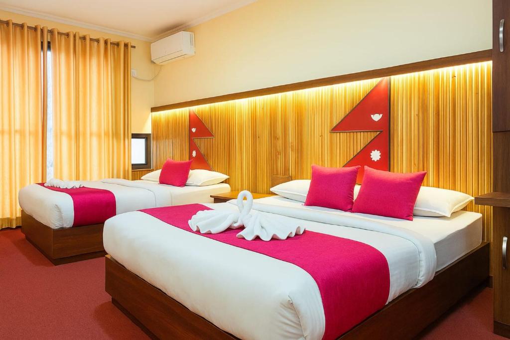 two beds in a hotel room with red and white pillows at Hotel Good one in Pokhara