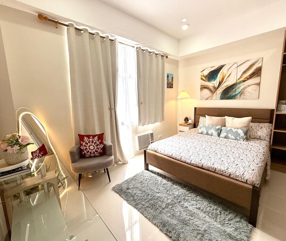 a bedroom with a bed and a chair and a window at Raph Staycation near Mactan Newtown in Lapu Lapu City