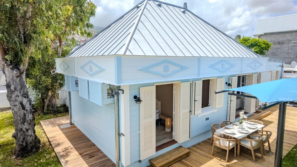 a blue house with a roof on a deck at La Villa Bleue, Pieds dans l'eau in Saint-Leu