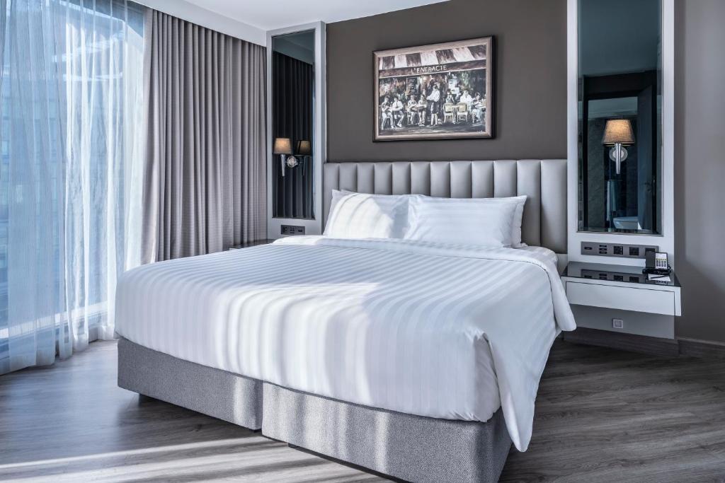 a bedroom with a large white bed and a window at Quartier by Montraj Sukhumvit Bangkok in Bangkok