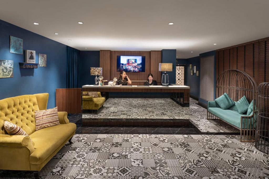A stylish hotel lobby with a reception desk, lounge seating and patterned tile flooring.