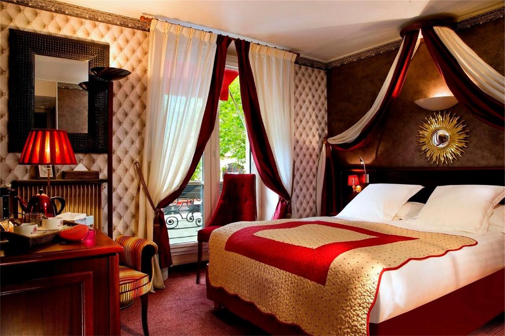 a bedroom with a bed and a desk and a window at Hotel Britannique in Paris