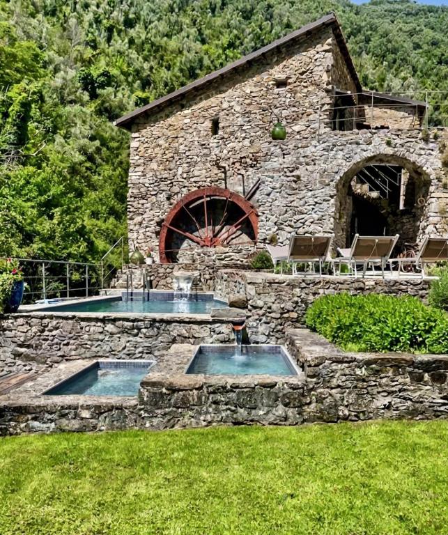 a stone building with two pools in a yard at Old Mill in Pigna