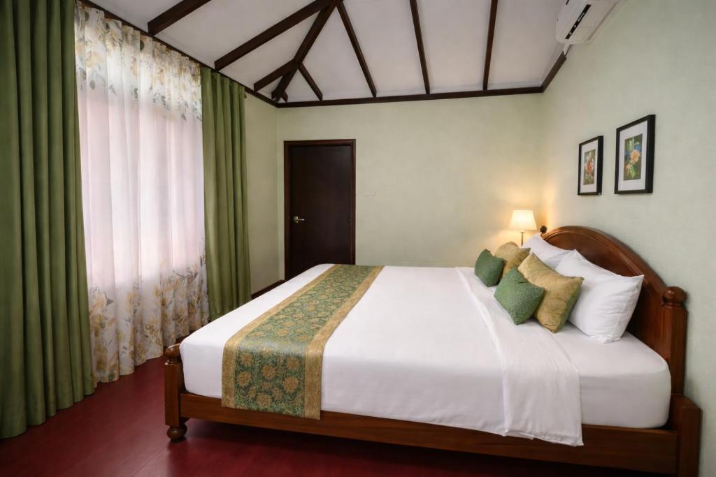 a bedroom with a large bed with green curtains at KADUPUL Hiriketiya in Hiriketiya