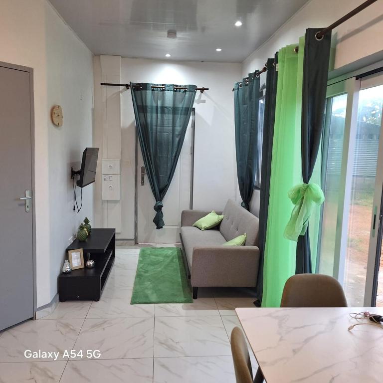 a living room with a couch and a green curtain at Fayalobi in Saint-Laurent du Maroni