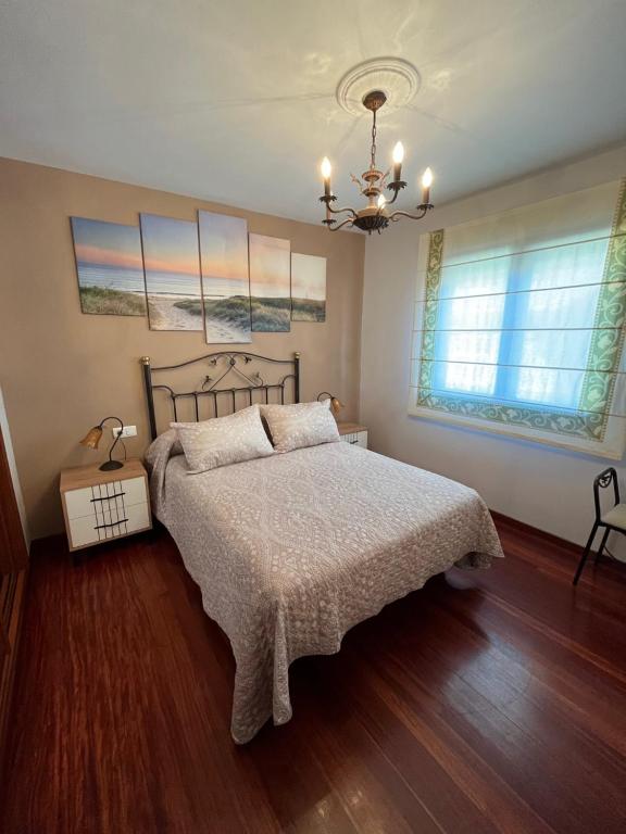 a bedroom with a bed and a chandelier at Alquiler Vacacional en Ribeira in Ribeira