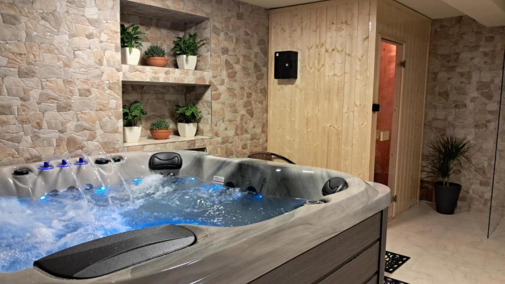 a hot tub in a bathroom with a stone wall at Dom Wczasowy U Góralki in Murzasichle