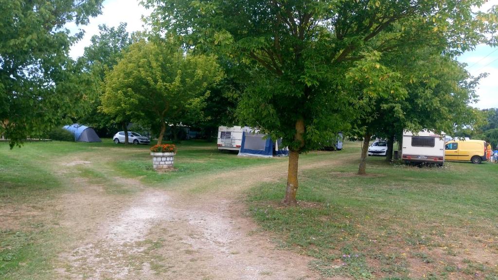 a dirt road in a field with trees and tents at Camping à la Ferme de la Touche in Marennes