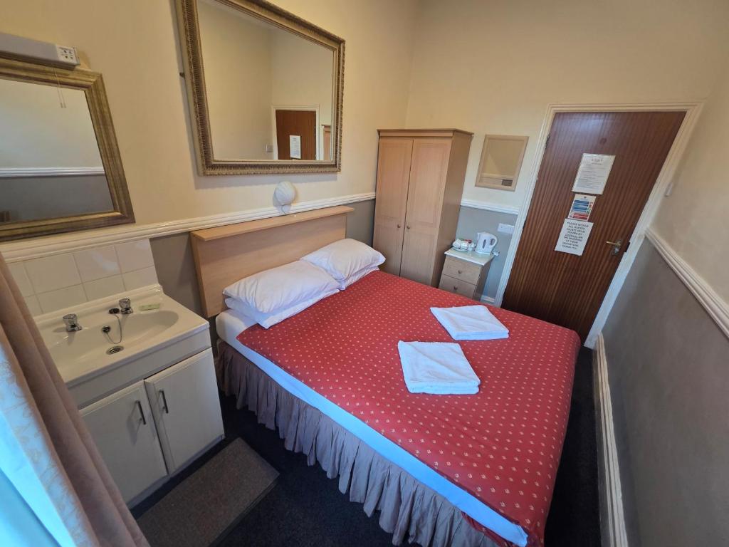 a small room with a bed and a sink at Westholme Hotel in Blackpool
