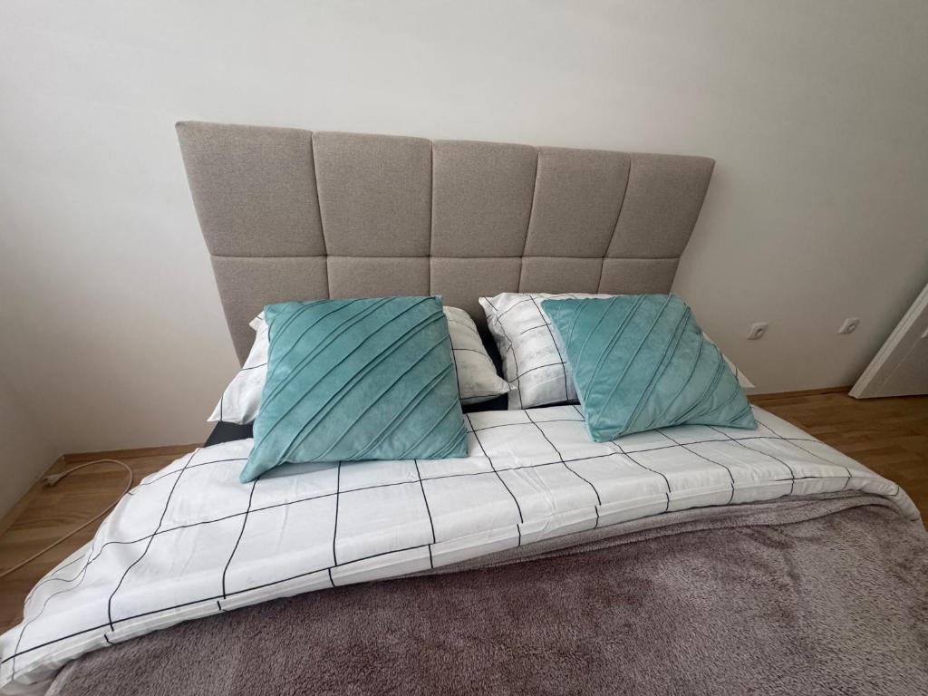 a bed with two blue pillows on top of it at Apartman "Paolo" Istočno Sarajevo in Vranješ