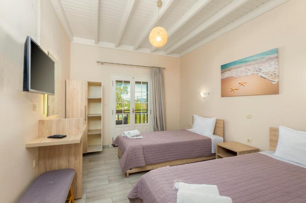 a hotel room with two beds and a television at Potamos Apartments in Sidari