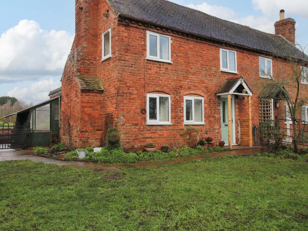 a brick house with white windows and a yard at 1 Dingle Cottage in Worcester