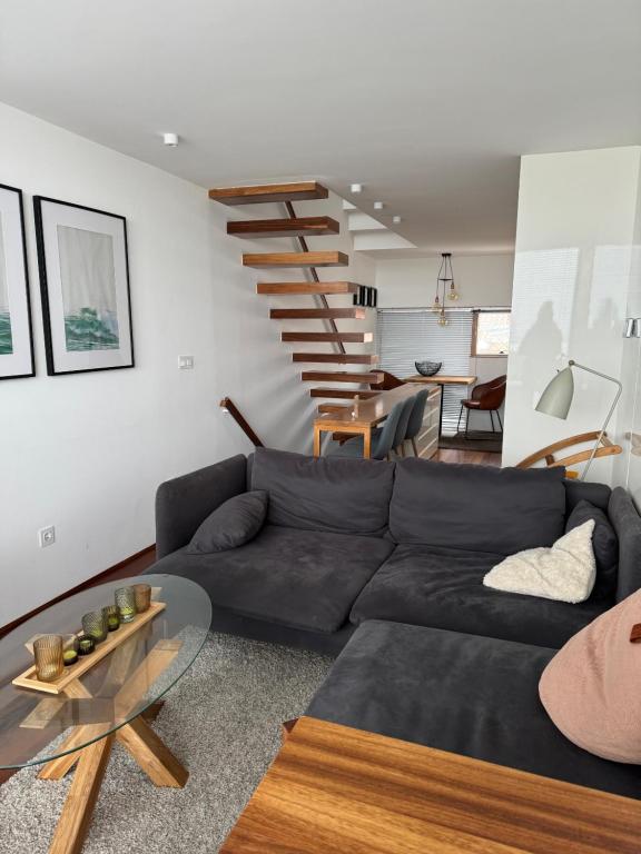 a living room with a black couch and a staircase at Casa dos Coelhos in Moledo