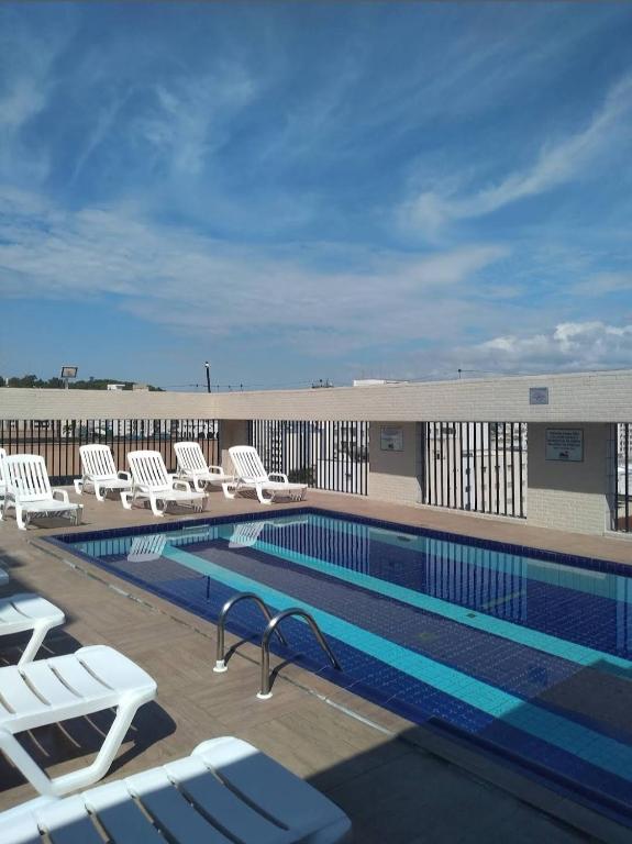 a swimming pool with white lounge chairs next to a building at Prime Flat Palladium Mar & Piscina in São Vicente