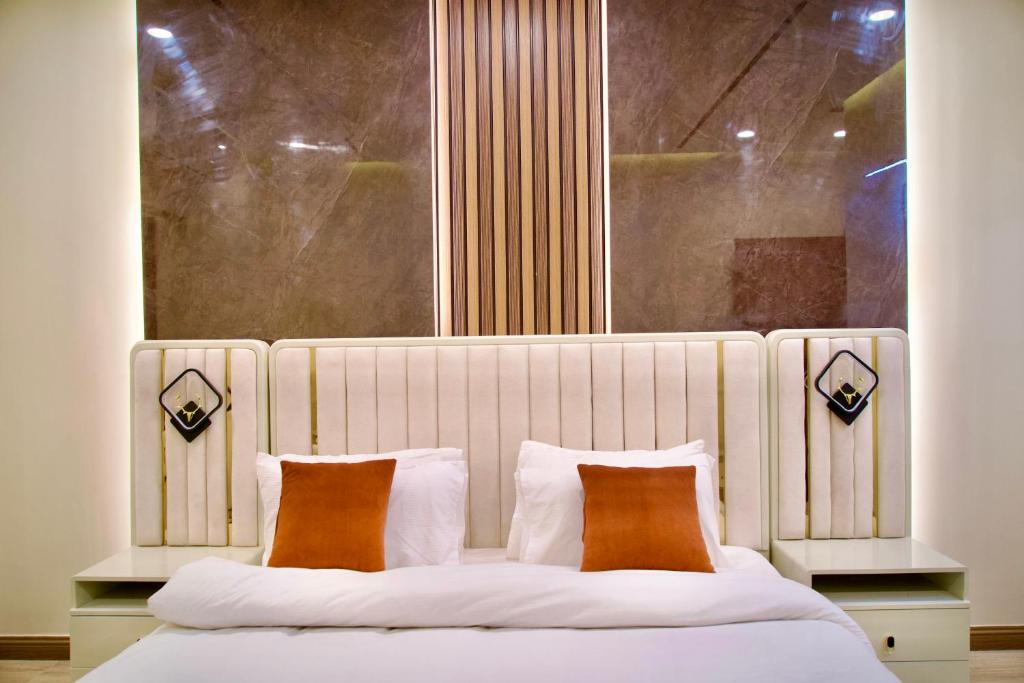 a bedroom with a white bed with two orange pillows at Executive 2BHK in Zeta Mall in Islamabad