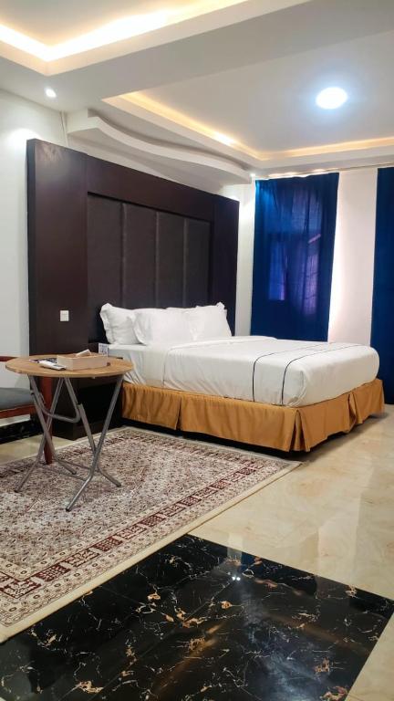 a bedroom with a large bed with a table and a table at فندق جولدن نيو روز بلازا جازان in Jazan
