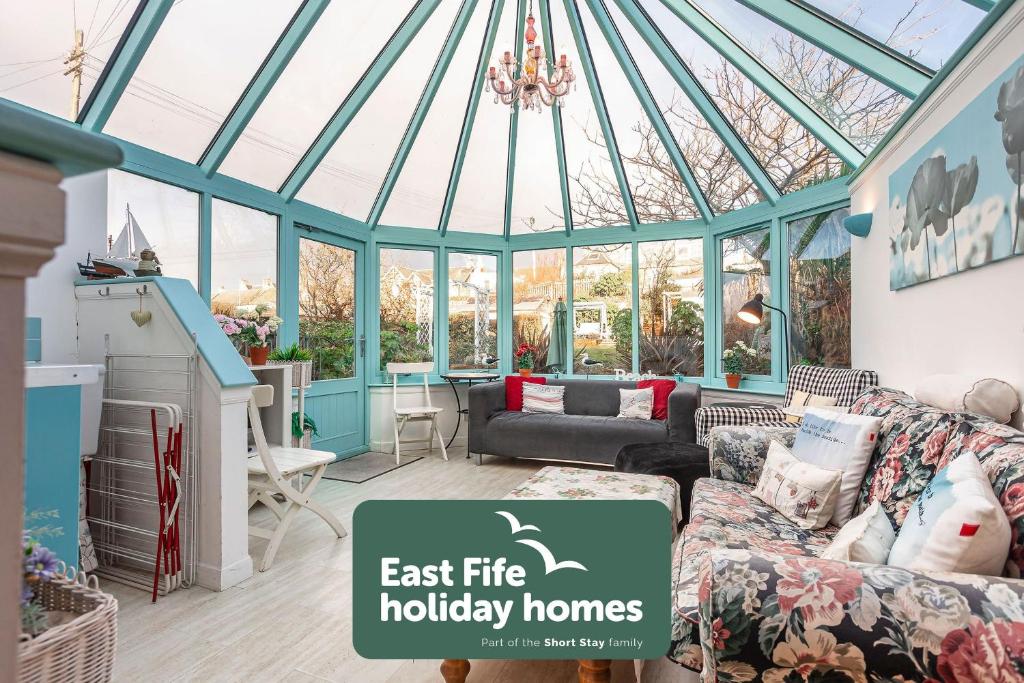 a room with a conservatory with a couch and a chandelier at Stoneywell Cottage - Elie in Elie