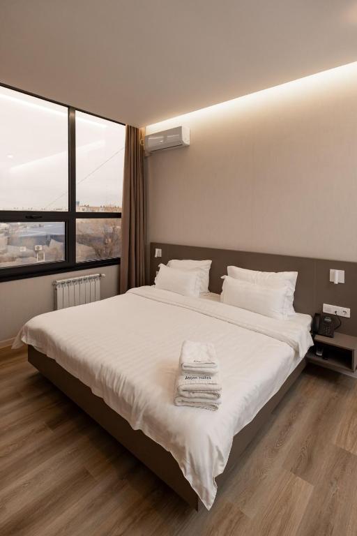 a bedroom with a large bed with white sheets and pillows at Aston Hotel in Aktau