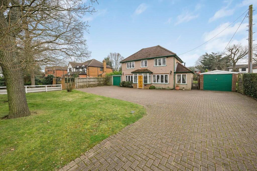 a house with a green garage and a driveway at The Sweet Spot in Ickenham