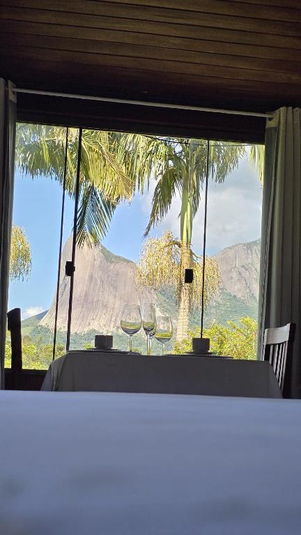 a table with two wine glasses in front of a window at Chalé Vista Pedra Azul in Domingos Martins