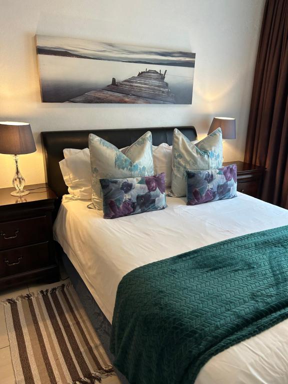 a bedroom with a bed with pillows and a picture of a ship at Alendo Apartments in Johannesburg