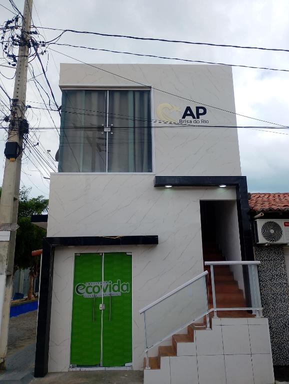 a white building with a green door and stairs at AP Brisa do Rio in Galinhos