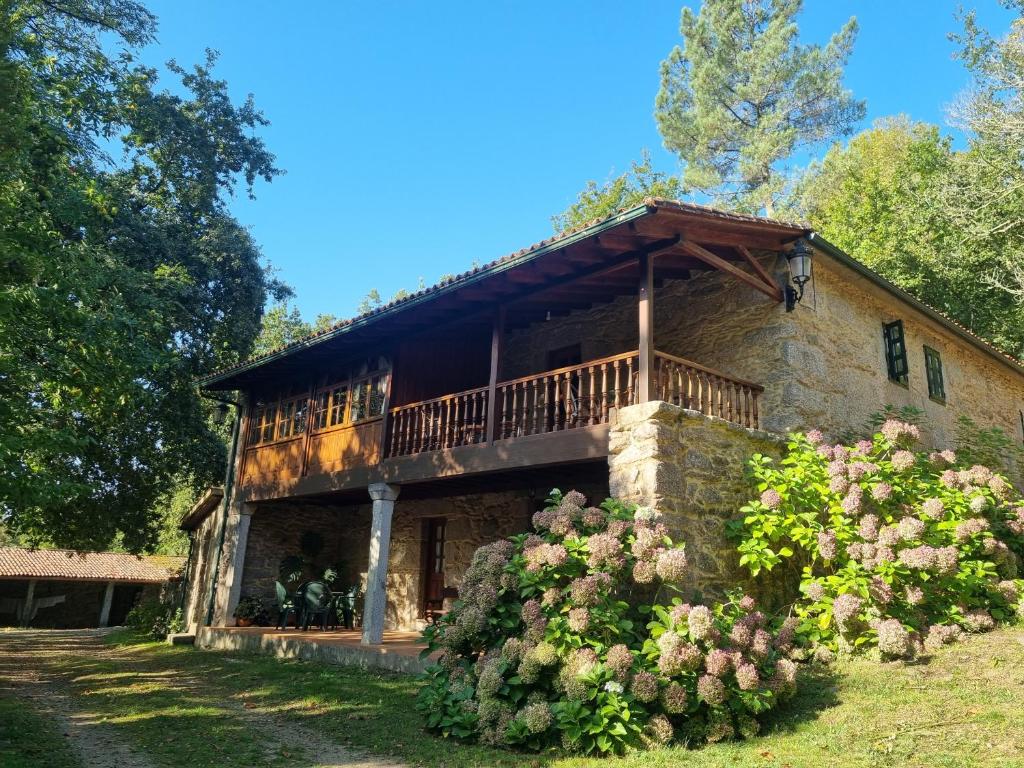 a stone house with a balcony on top of it at A Regueira Habitaciones in Alján