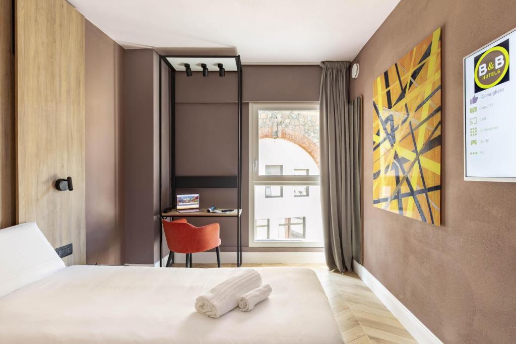 a bedroom with a bed with a chair and a window at B&B Hotel Genova City Center in Genoa