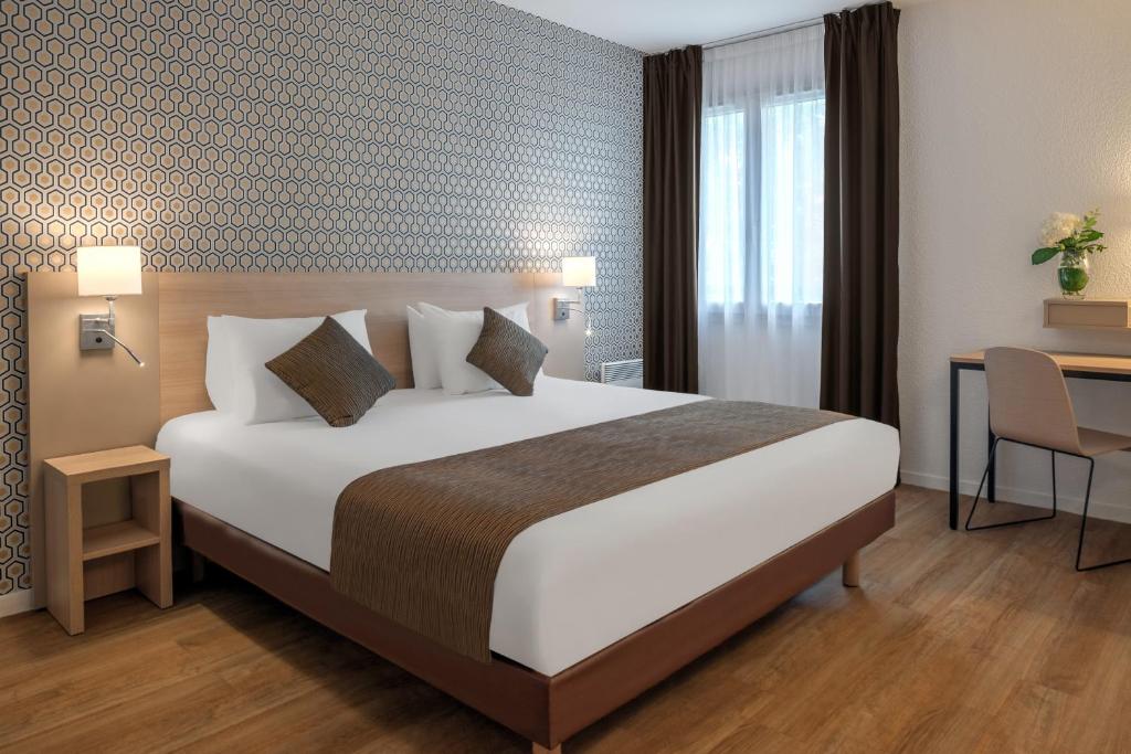 a hotel room with a large bed and a desk at Citadines Bastille Gare de Lyon Paris in Paris